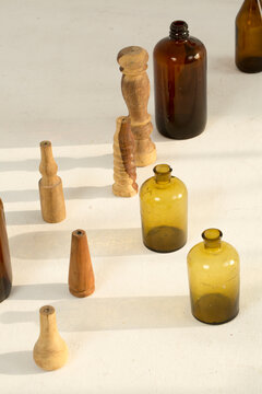 Glass bottles of different size placed on a white floor with shadows forming