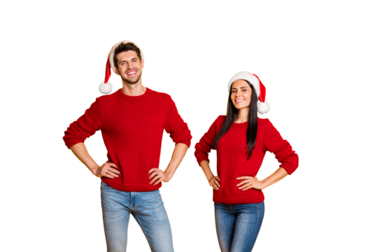 Portrait of cheerful spouses in santa claus hats look stand isolated over yellow background