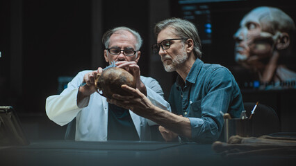 Two archaeologists take measurements of prehistoric human skull, conduct scientific research, use...