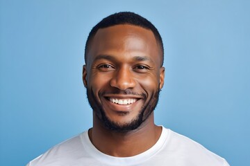Obraz premium Portrait of a cheerful black man with white teeth, isolated against a blue background. Studio shot with a joyful expression.