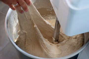 the baker conducts a dough test for the consistency of the dough in a mixing bowl