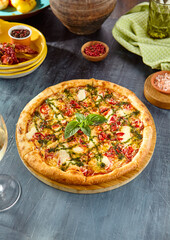 Fresh Margherita Pizza with Basil Pesto Sauce and Tomatoes on Rustic Table