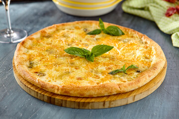 Delicious Four Cheese Pizza (Quattro Formaggi) on Wooden Board with Basil Leaves