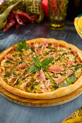 Delicious Smoked Salmon and Pesto Pizza on Wooden Board with Fresh Basil and Rustic Setting