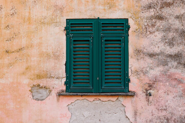 Fototapeta premium Traditional Italian dark green wooden shutters the old stone villa facade wall 