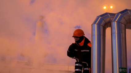 Fototapeta premium Night shift worker in highly demanding industrial environment, surrounded by steam and metal equipment. Protective gear underscores focus on safety and high-risk nature of work.