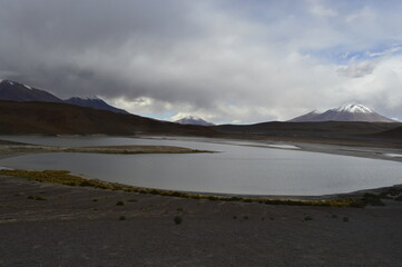 Obraz premium Nuvens de chuva sob lago e montanhas com pico nevado