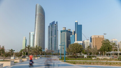 Corniche boulevard beach park along the coastline in Abu Dhabi timelapse with skyscrapers on background.
