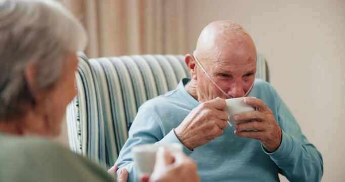 Coffee, conversation and smile with old couple in living room of retirement home to relax for wellness. Face, happy or love and man with oxygen talking to woman in apartment for bonding or break