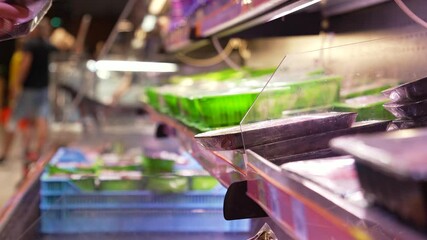 A woman takes packaged meat from the refrigerator. Supermarket. Close-up