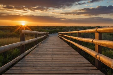 Obraz premium Wooden deck that goes down to the beach sand, low vegetation on the side, sunset in the background.