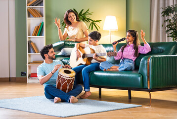 Happy Indian Asian family making music together at home; singing, playing instruments, enjoying time