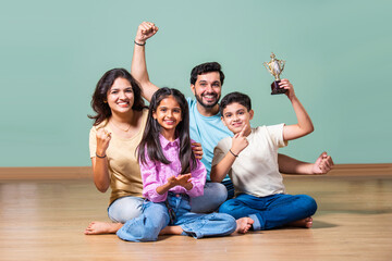 Indian boy or girl holding a trophy, celebrated by proud parents standing beside in a joyful moment