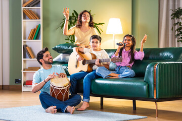 Happy Indian Asian family making music together at home; singing, playing instruments, enjoying time