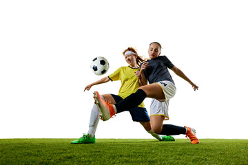 Two young athletic women, soccer players in their 20s, engaged in close tackle on soccer field, both intensely focused on winning ball. Concept of sport, competition, tournament, games, event.