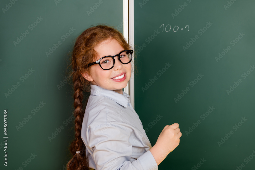 Wall mural Portrait of little schoolchild girl hodl chalk wear uniform isolated on blackboard background