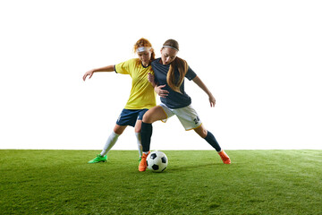 Determined young woman, mid-20s, soccer player, mid-air performing kick, fully focused on ball against white background. Concept of sport, competition, tournament, games, event.