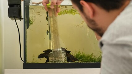 Man engaging in water change process using a siphon for aquarium maintenance