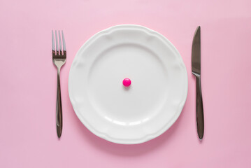 Top view of bright pink round tablet on a white plate on pink background. Creative tablets concept
