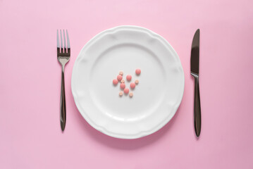 Top view of several pink round tablets on a white plate on pink background. Creative pills concept