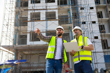 Two Professional Architects Engineer Working on Personal laptop computer at house construction site. Product quality Inspection