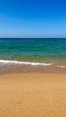 Turquoise water, sandy beach and blue sky at Faro Beach, Portugal