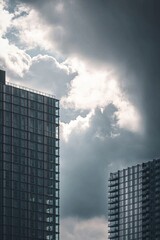 The sharp lines of a distant modern building standing against a cloudy sky, with the urban landscape compressed behind it. 