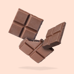 Pieces of sweet chocolate falling on beige background