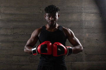 A powerful African American boxer in red gloves prepares for a punch in a gym, demonstrating...
