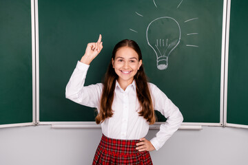 Photo of cute teen schoolgirl diligent electric bulb eureka brilliant idea dressed stylish uniform classroom blackboard background