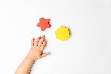 A toddler is playing with multi colored wooden block toys, sitting on a white table, top shots