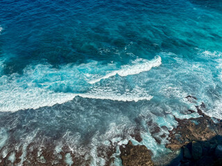 Crystal clear ocean water meeting rocks and coral reefs at Diamond Beach - Nusa Penida, Bali, Indonesia