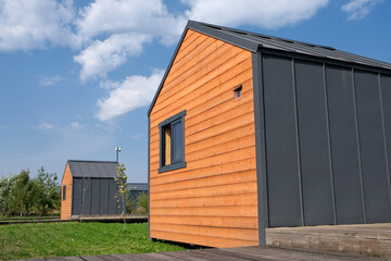 Two small barn style houses on a lot with a path under a blue sky.