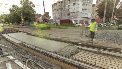 Naklejka premium Concrete works for road construction with many workers and mixer timelapse hyperlapse