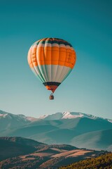 Obraz premium A colorful hot air balloon ascends over a mountain range with snow-capped peaks.