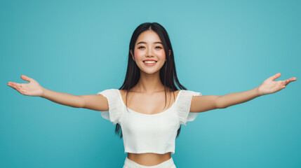 Smiling Asian woman with long straight hair in a white off-shoulder crop top, arms wide open against a teal background, expressing joy and welcome