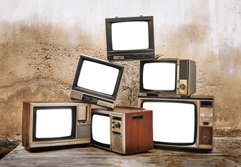 Retro old televisions pile with cut out screen, on floor in front of old brick wall. Antique and vintage style photo, TVs blank white screen display, clipping path
