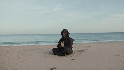 Fototapeta premium Monk Collected In Prayer Sitting On The Beach In The Evening