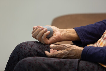 Elderly woman doing rubber ball for exercise fingers, palm ,hand and foot muscle with caregiver take care.