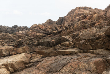 Huge dark and slippery rocks against the cloudy sky. Untouched nature.