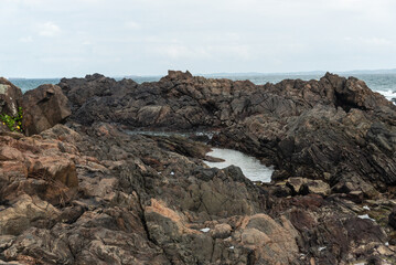 Huge dark and slippery rocks against the cloudy sky. Untouched nature.