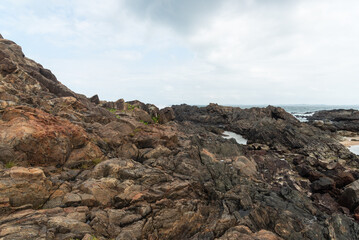 Fototapeta premium View of dark sea rocks against the ocean and cloudy sky. Preserved nature.