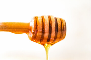 honey dripping from a wooden dipper, isolated on white background