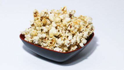 Caramel Popcorn in black bowl isolated on white background.