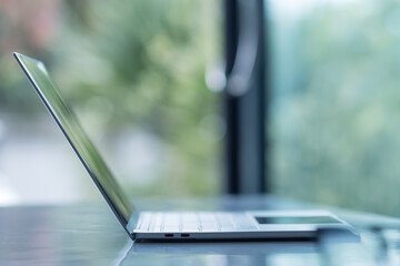 A sleek modern laptop is positioned on a table, showcasing its minimalist design and reflecting natural light from a nearby window, perfect for a productive workspace