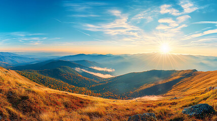 Breathtaking panoramic view of mountain landscape with blue sky and sun rising over horizon, showcasing vibrant autumn colors and rolling hills.