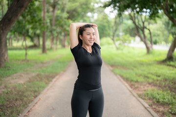 Asian woman stretching to warm up before going for a run in the park. Hair care concept before exercise to reduce injuries. Health care affected by sports.