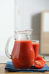 Tasty tomato juice in jug, glass and vegetable on wooden table indoors