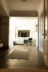 Modern hallway leading to bright bathroom with large mirror and vanity