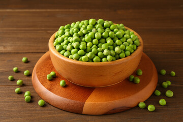 Fresh green peas in bowl on wooden table